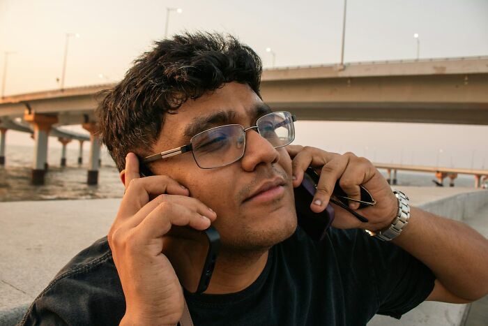 A man in glasses looks stressed, holding two phones to his ears, perhaps indicating reasons to rage quit jobs.