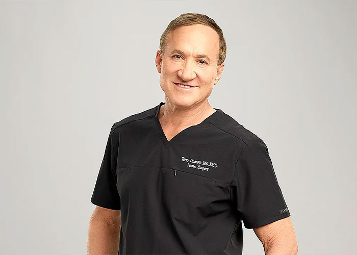 Doctor in black scrubs smiling, expert on male celebrities looking unrecognizable