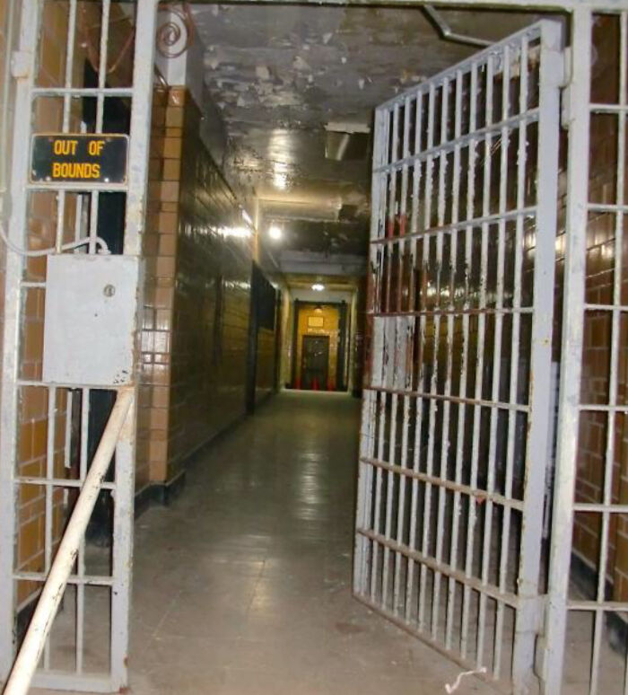 Dimly lit corridor with rusty jail bars and out of bounds sign in Backrooms levels