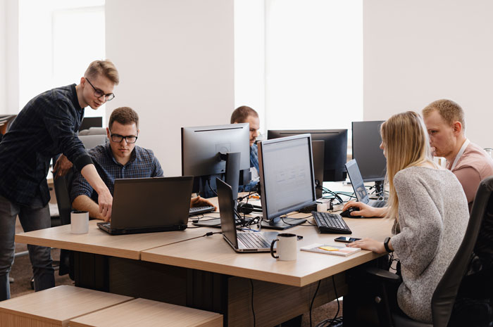 Team collaborating in office with AI technology on computers