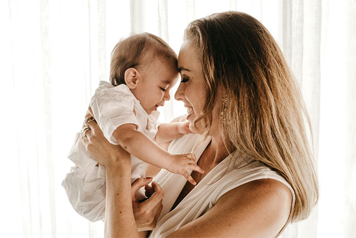 Mother lovingly holding her baby close indoors family moments Mother lovingly holding her baby close indoors family moments