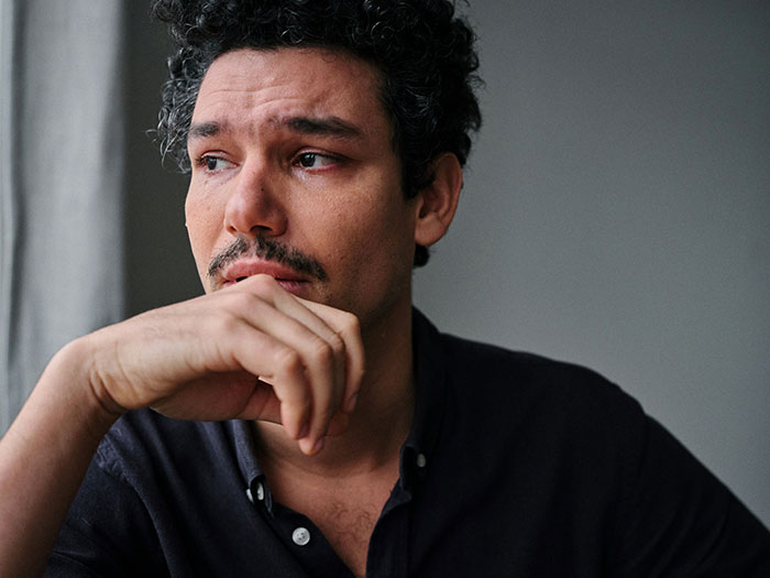 A man with a pensive expression, possibly feeling regret. He looks sad, reflecting on leaving his wife and kids.