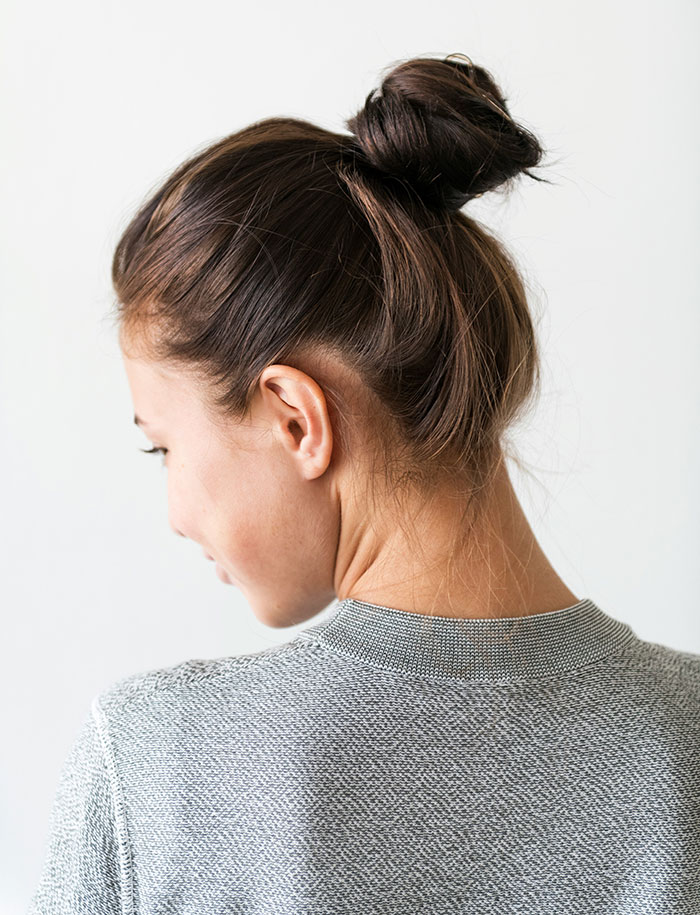 Woman with a messy bun and grey sweater, looking away, reflecting on regrets after leaving a wife.