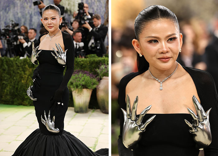 A celebrity at the Met Gala 2026 in a black gown with striking silver extra arms and hands.