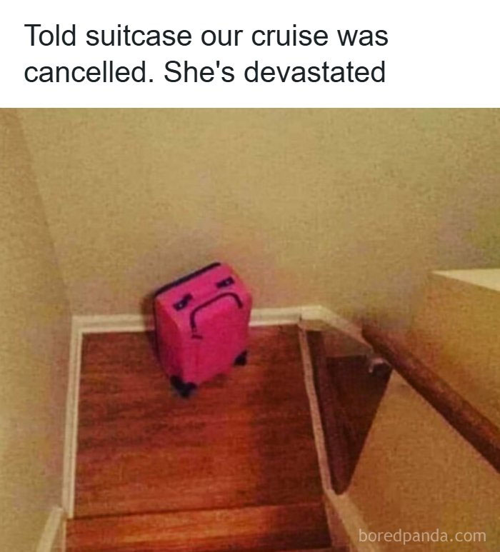 A pink suitcase with a sad face drawn on it, sitting at the bottom of stairs, creating a funny travel meme.