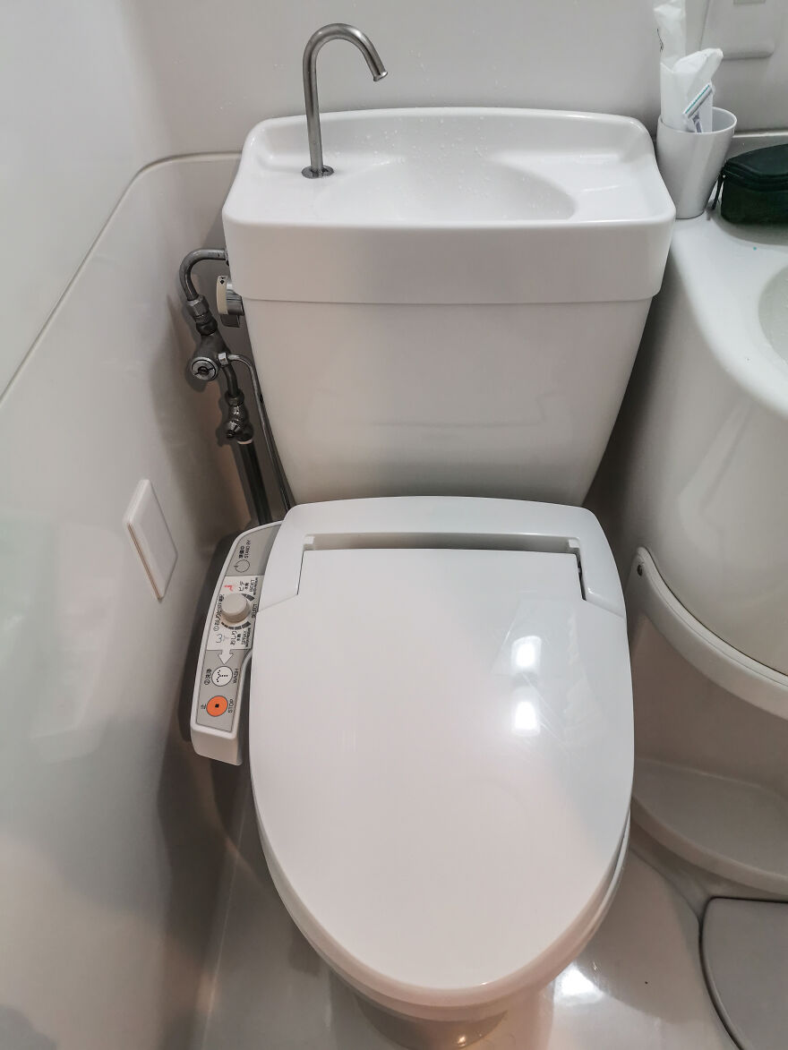 A white Japanese toilet with an integrated sink on top of the tank, showcasing practical design.