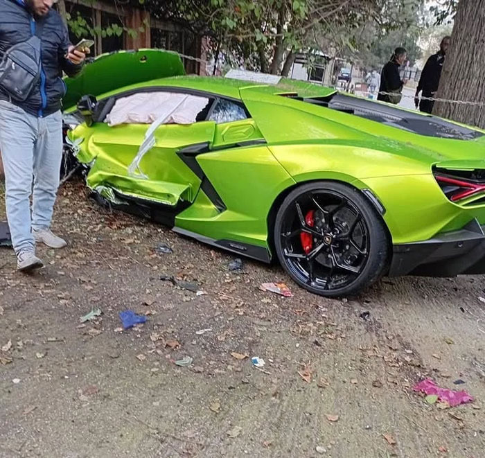A bright green sports car, heavily damaged in an accident, with airbags deployed. Bystanders look on, illustrating expensive fails.