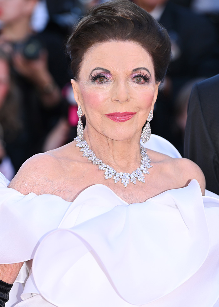 A glamorous older woman, a Boomer, with elaborate makeup and diamond jewelry, wearing a white off-the-shoulder gown. A glamorous older woman, a Boomer, with elaborate makeup and diamond jewelry, wearing a white off-the-shoulder gown.