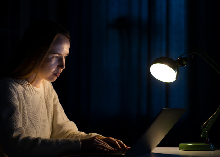 Woman working late on laptop under desk lamp anxiety-inducing truths