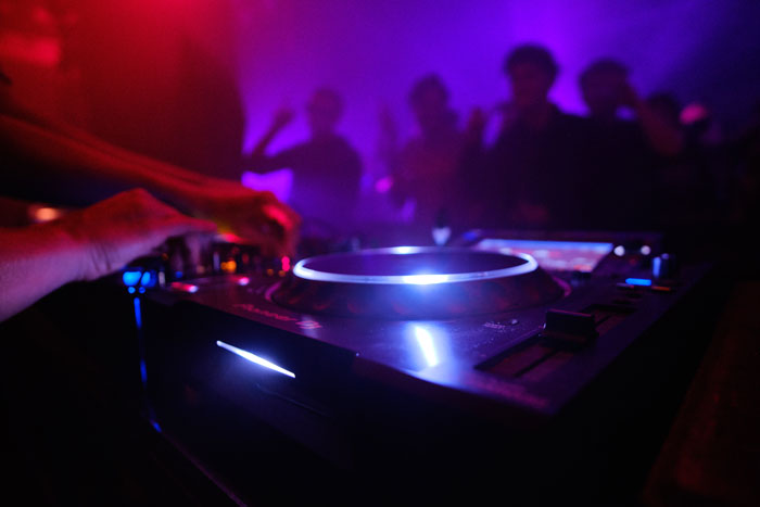 DJ mixing music at nightclub with purple lighting
