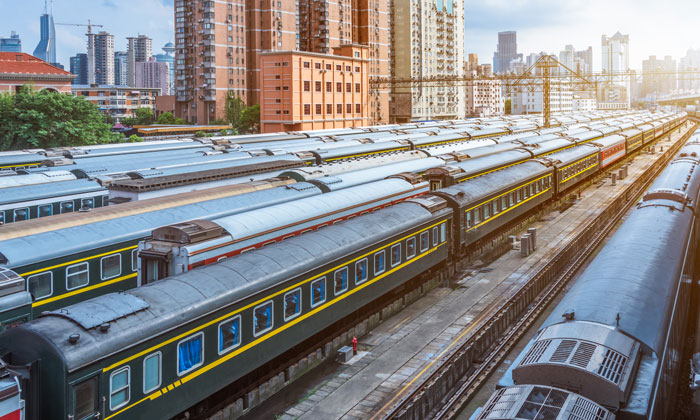 European train station with multiple trains and city buildings