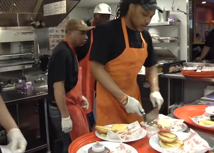 Hooters kitchen staff preparing food, illustrating restaurant rebrand Hooters kitchen staff preparing food, illustrating restaurant rebrand