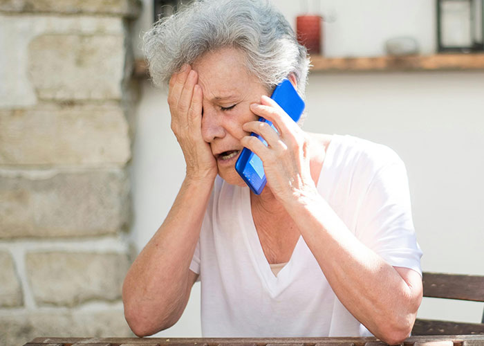 Distressed elderly woman talking on a smartphone