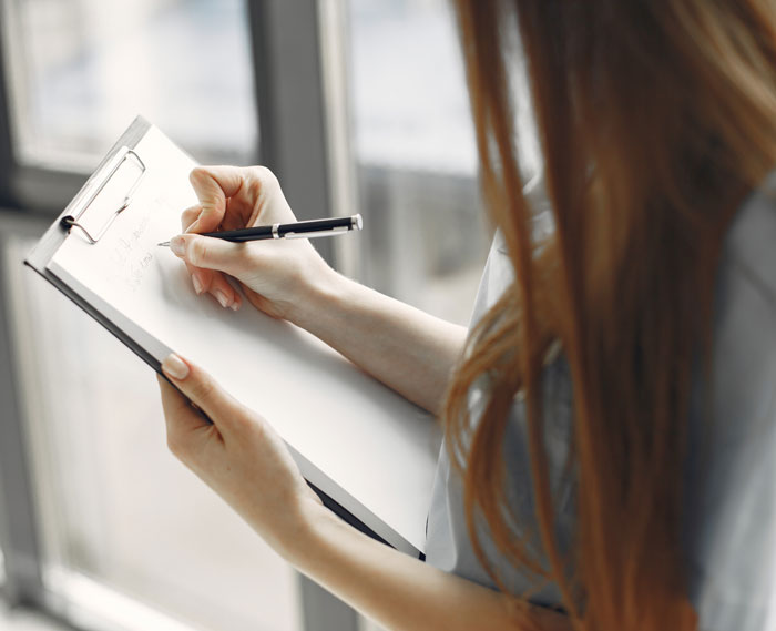 Person writing notes on a clipboard close-up for statistics research