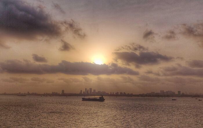 Sunset over city skyline and sea with a ship in the water in incredible photos