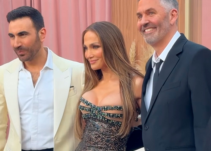 Jennifer Lopez posing with two men at a premiere event wearing an elegant dress