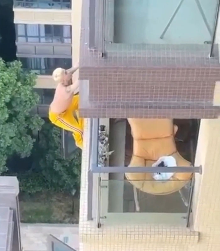Man wearing yellow pants climbing a rooftop ledge high above ground