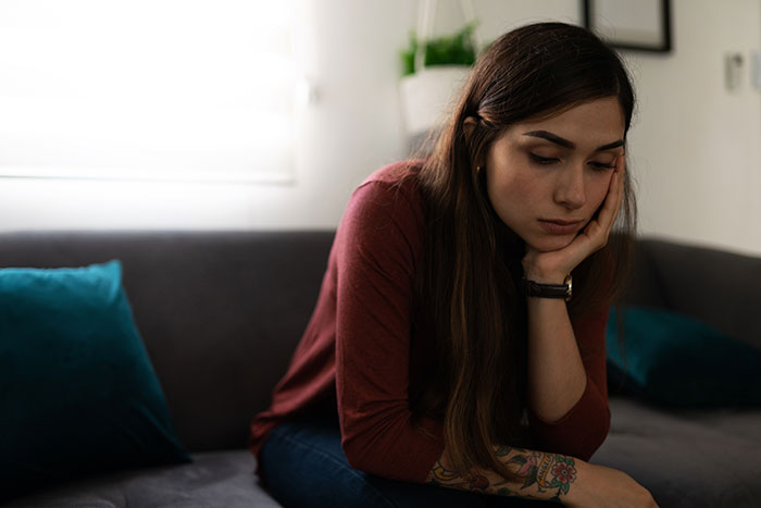 Sad woman sitting alone, reflecting on relationship breakup and baby plans