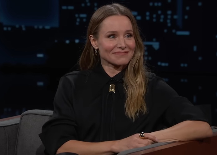 Kristen Bell on a talk show, smiling slightly, showcasing celebrity saving habits and how to be frugal.