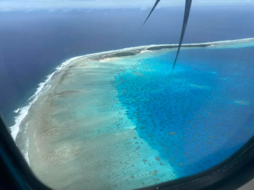 Aerial view of an isolated island with vibrant blue waters and coral reefs, perfect for adventurers seeking isolated places.
