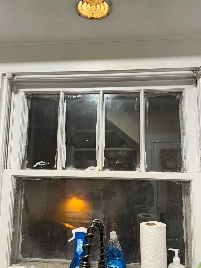 A dirty kitchen window, showing poor quality work by a very expensive contractor, with caulk smeared on the glass.