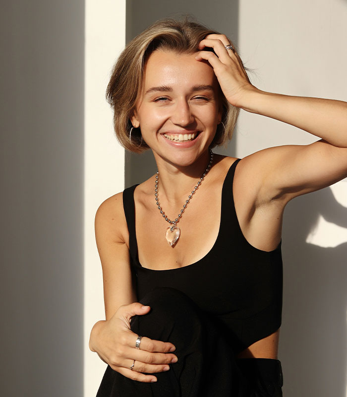 Smiling woman in black tank top posing with relaxed confident pose