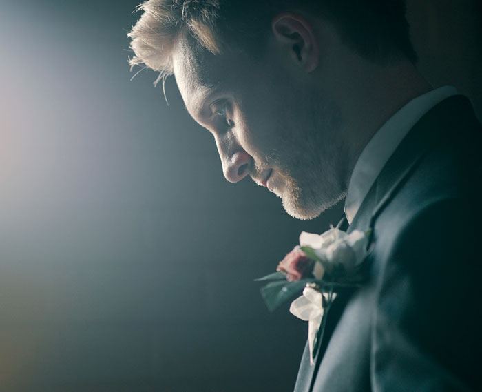 Groom in suit looking thoughtfully down with wedding boutonniere