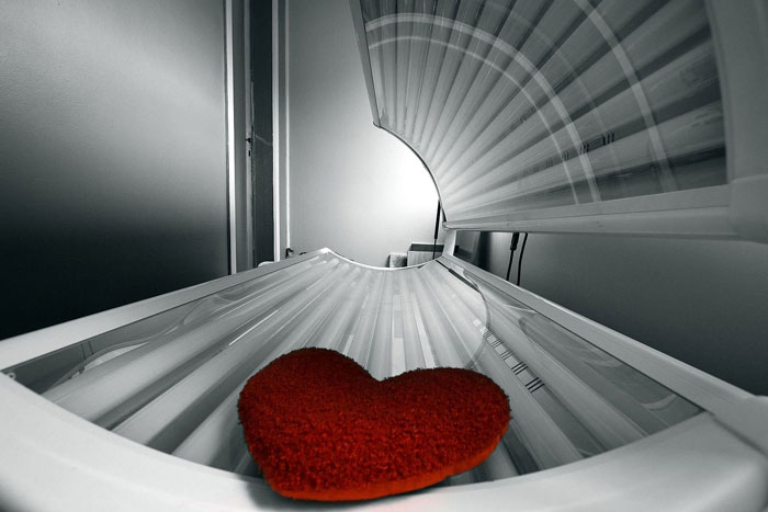 Red heart on tanning bed lamp inside for statistics about tanning and health