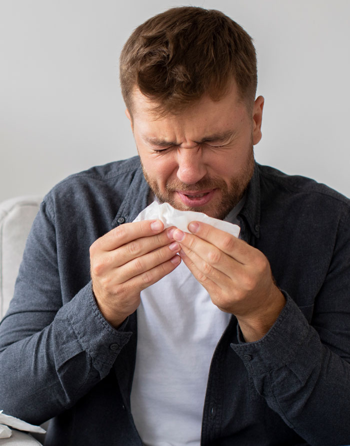 Man sneezing into tissue depicting illness and science facts