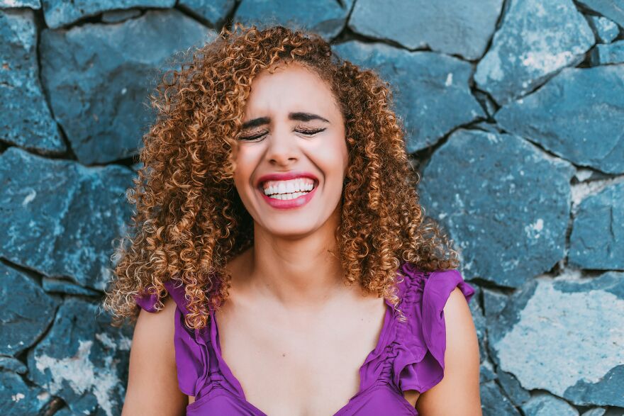 Woman laughing joyfully with eyes closed showing happy crying emotion