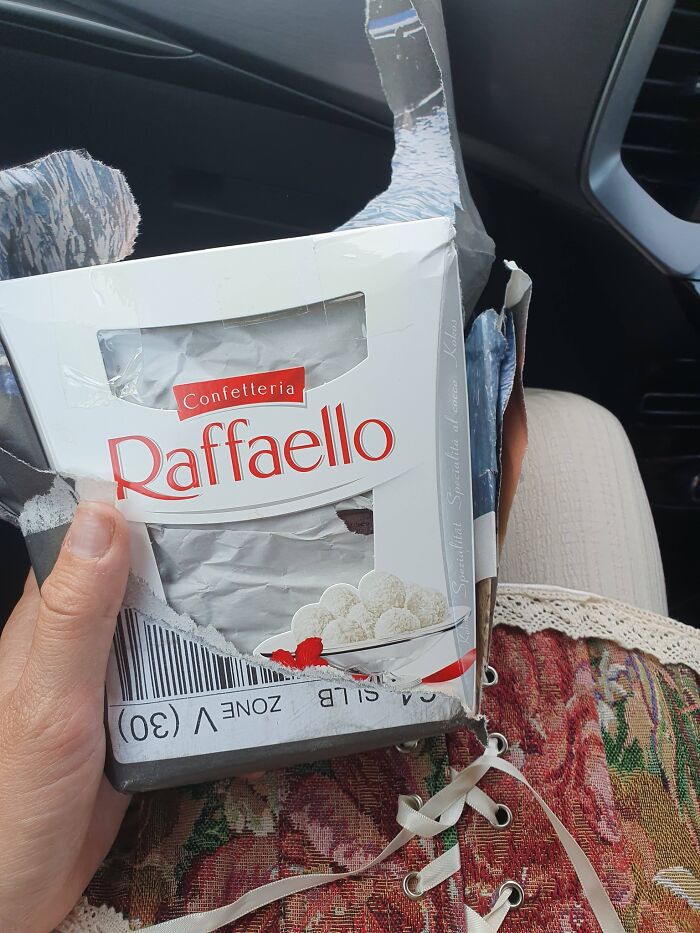 Photo of damaged Raffaello box held by a person in a car seat