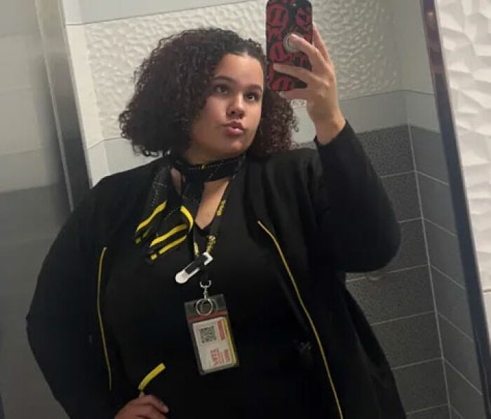 Woman taking mirror selfie in work uniform