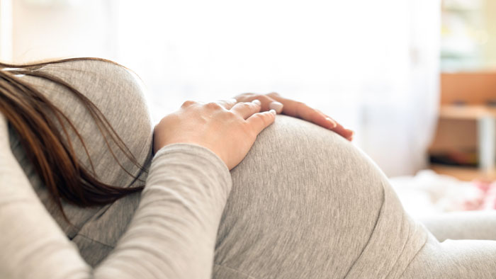Close-up of pregnant woman holding her belly representing surrogate pregnancy Close-up of pregnant woman holding her belly representing surrogate pregnancy
