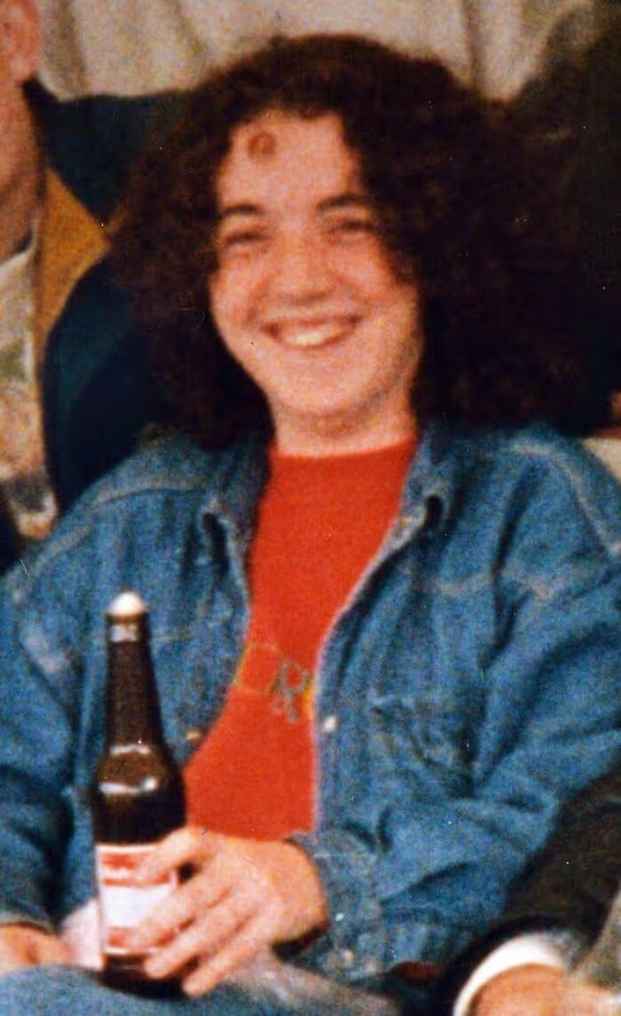 A young person with curly hair, smiling and holding a beer bottle. This image evokes disturbing d***h stories.