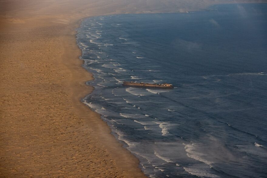 Aerial view of a shipwreck close to a barren coastline, highlighting the most isolated places on Earth.