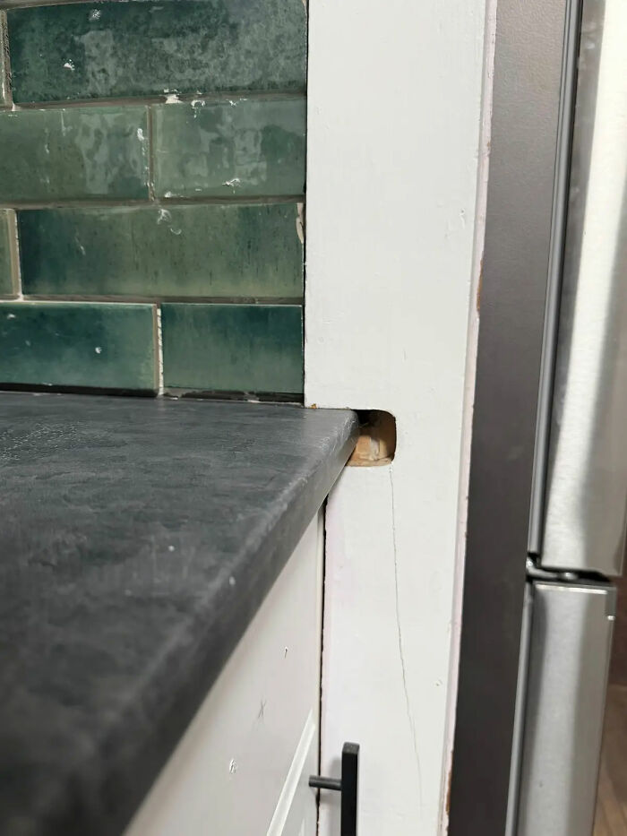 A poorly installed kitchen countertop next to a white cabinet, revealing a gap where the contractor made a mistake.