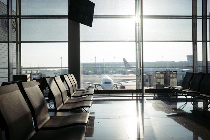 Empty airport waiting area with views of airplanes through large windows