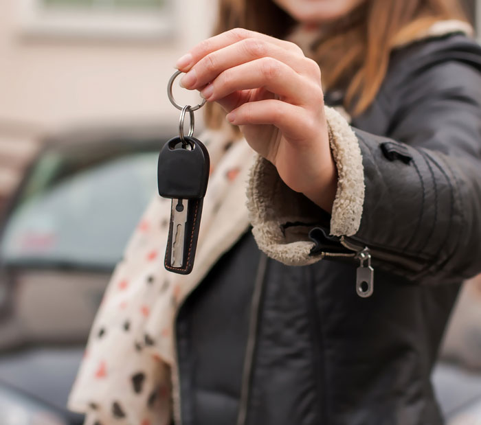 Woman holding car key in hand symbolizing glitch in the matrix ownership