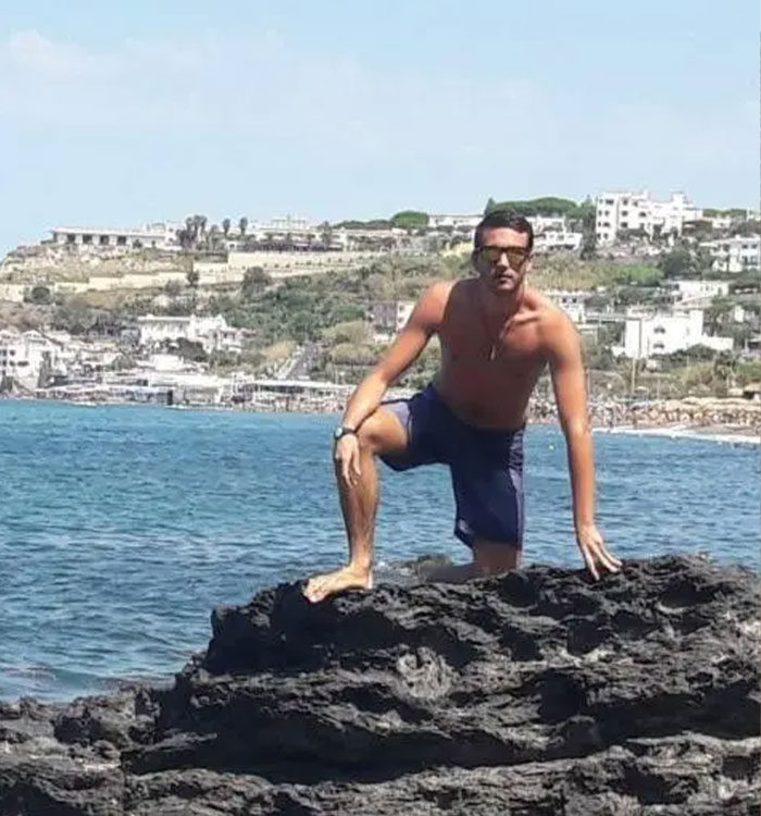 Shirtless man standing on rocks near water on Maldives diving holiday