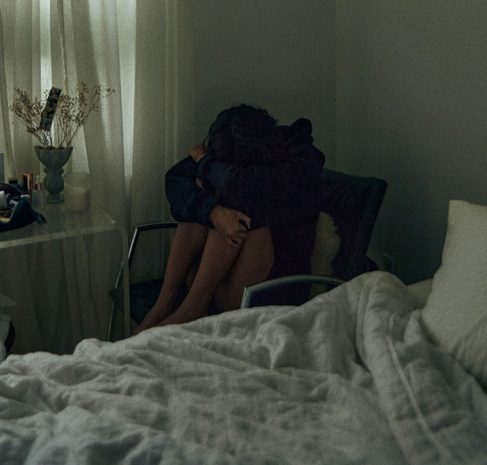 Person sitting alone in a dark room showing anxiety and mental health struggle