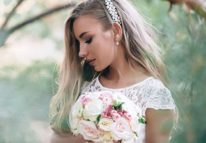 Bride holding bouquet looking down calmly in outdoor wedding setting
