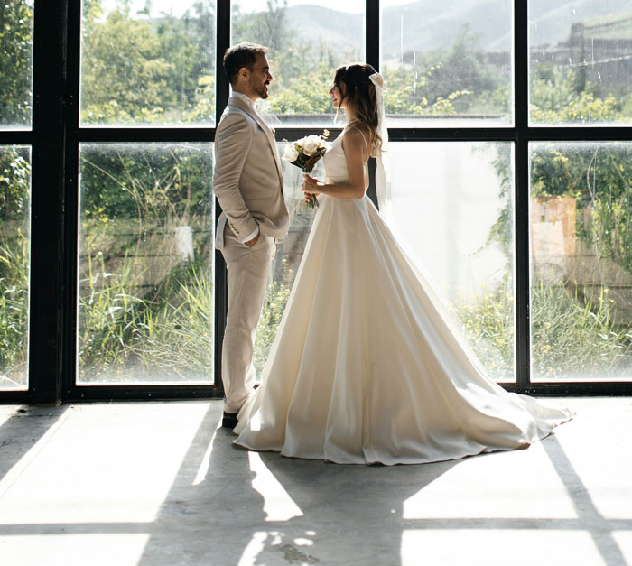 Bride and groom in wedding attire standing and smiling indoors