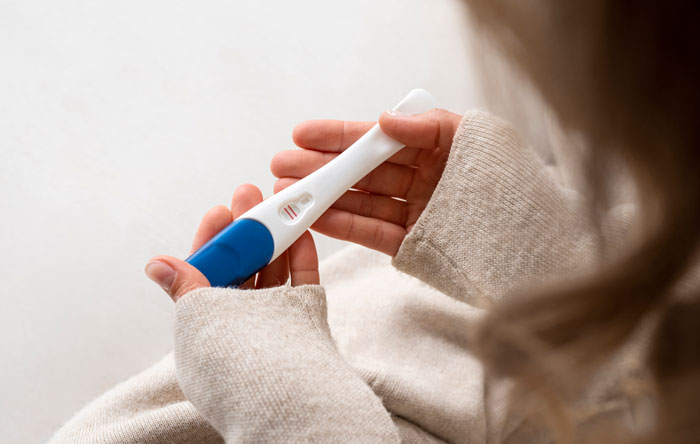 Woman holding positive pregnancy test symbolizing surrogate pregnancy Woman holding positive pregnancy test symbolizing surrogate pregnancy