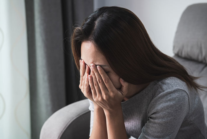 A woman crying with her face in her hands, sitting in a chair, reflecting the discovery of an ugly cover-up.