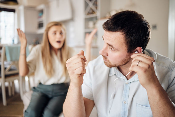 Man listening to headphones ignoring a frustrated woman in the background. Reflects very wrong facts on Reddit.