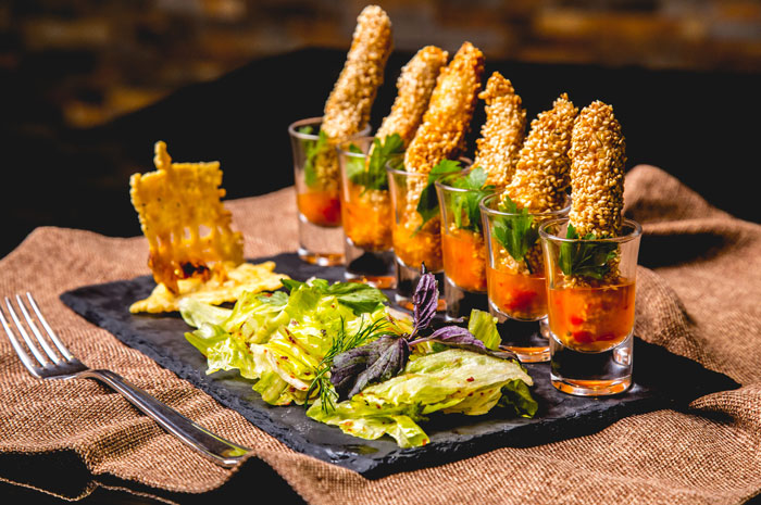 Artisinal breaded appetizers served in shot glasses with salad