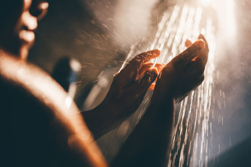 Hands feeling water spray in shower for mood boost