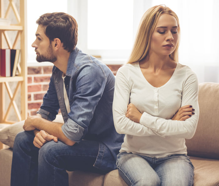 Husband and bride sitting back to back upset after bridezilla behavior during wedding