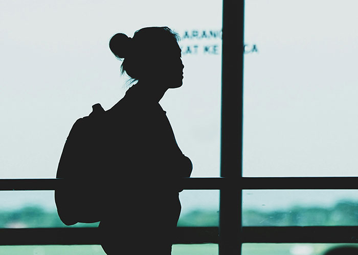 Silhouette of woman with backpack at window representing mysterious disappearances