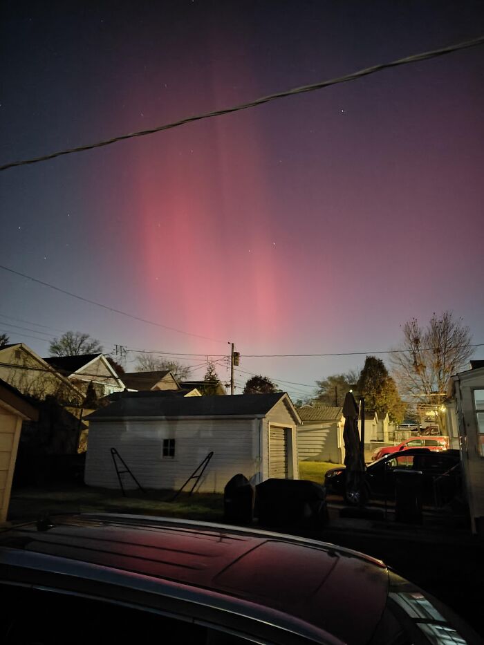 Red northern lights glowing above residential neighborhood rare moment photo